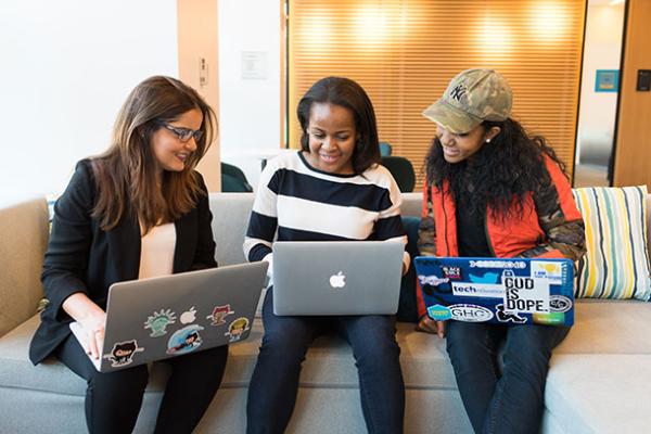 women at computers on couch